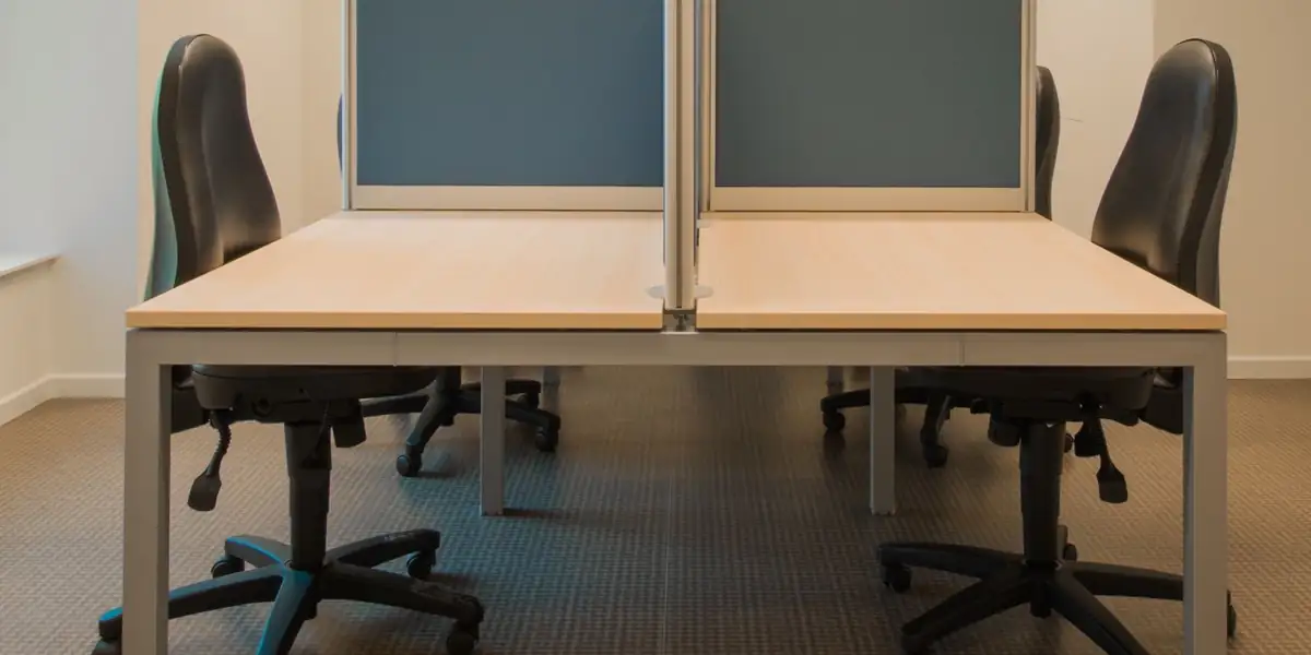 Black task chairs at shared office desks with blue divider panels
