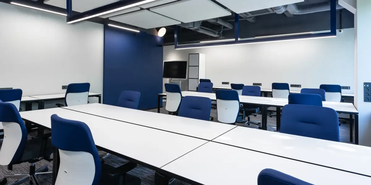 Modern workspace with rows of blue upholstered office chairs at white desks