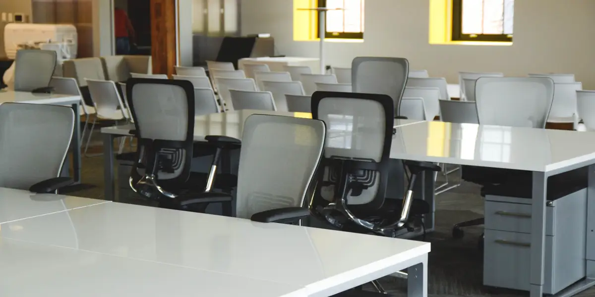 Rows of mesh-back ergonomic task chairs at white desks in a bright open-plan office