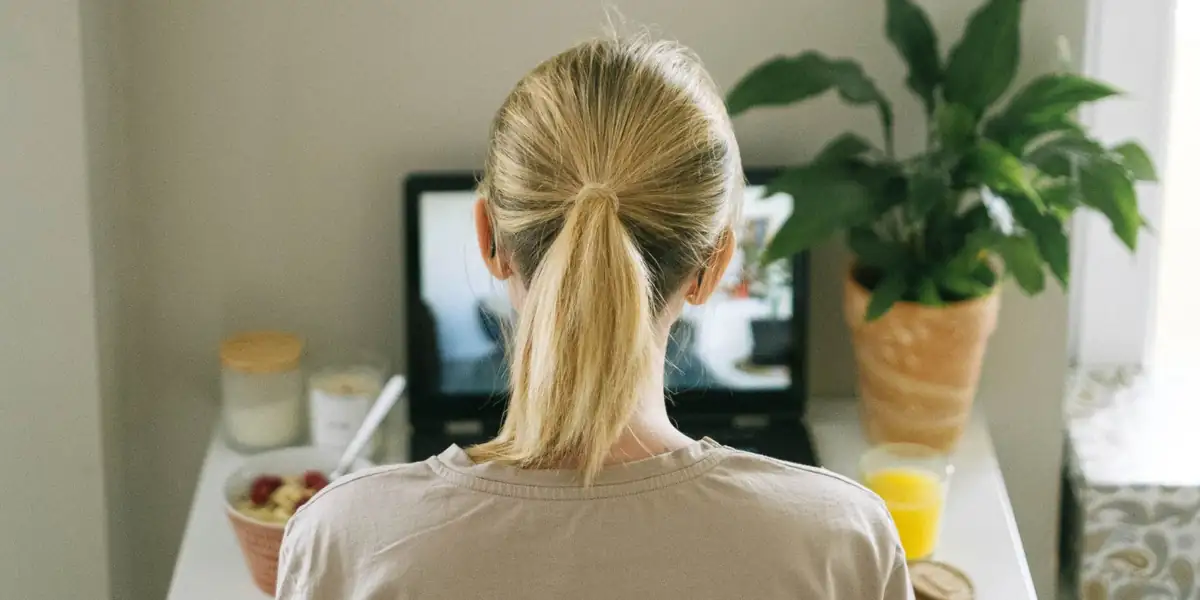Woman standing at a wall-mounted desk working on a laptop