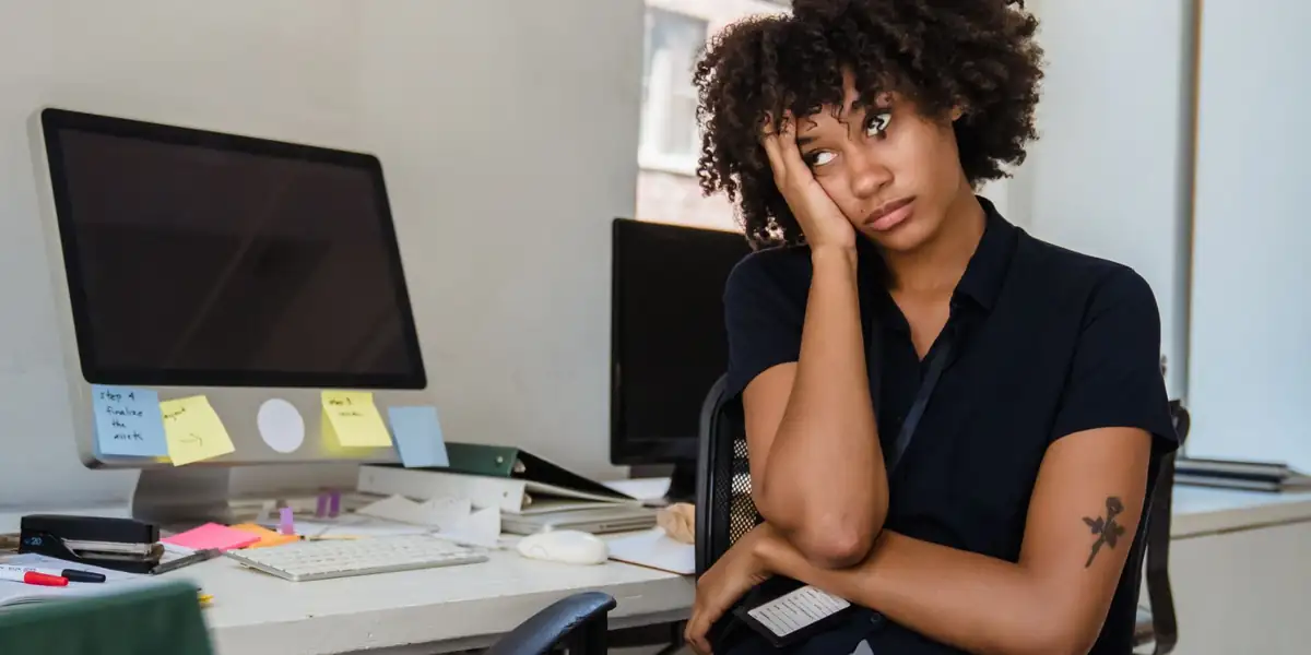 Tired woman sitting in a black office chair beside her desk
